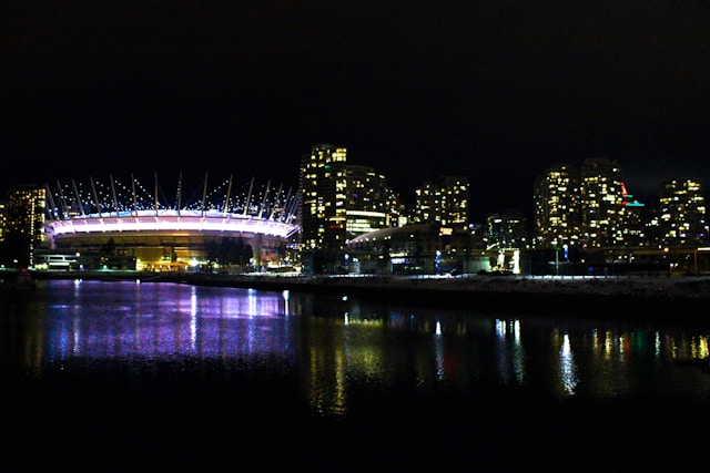 Illuminated stadium and city skyline reflected in the water at night